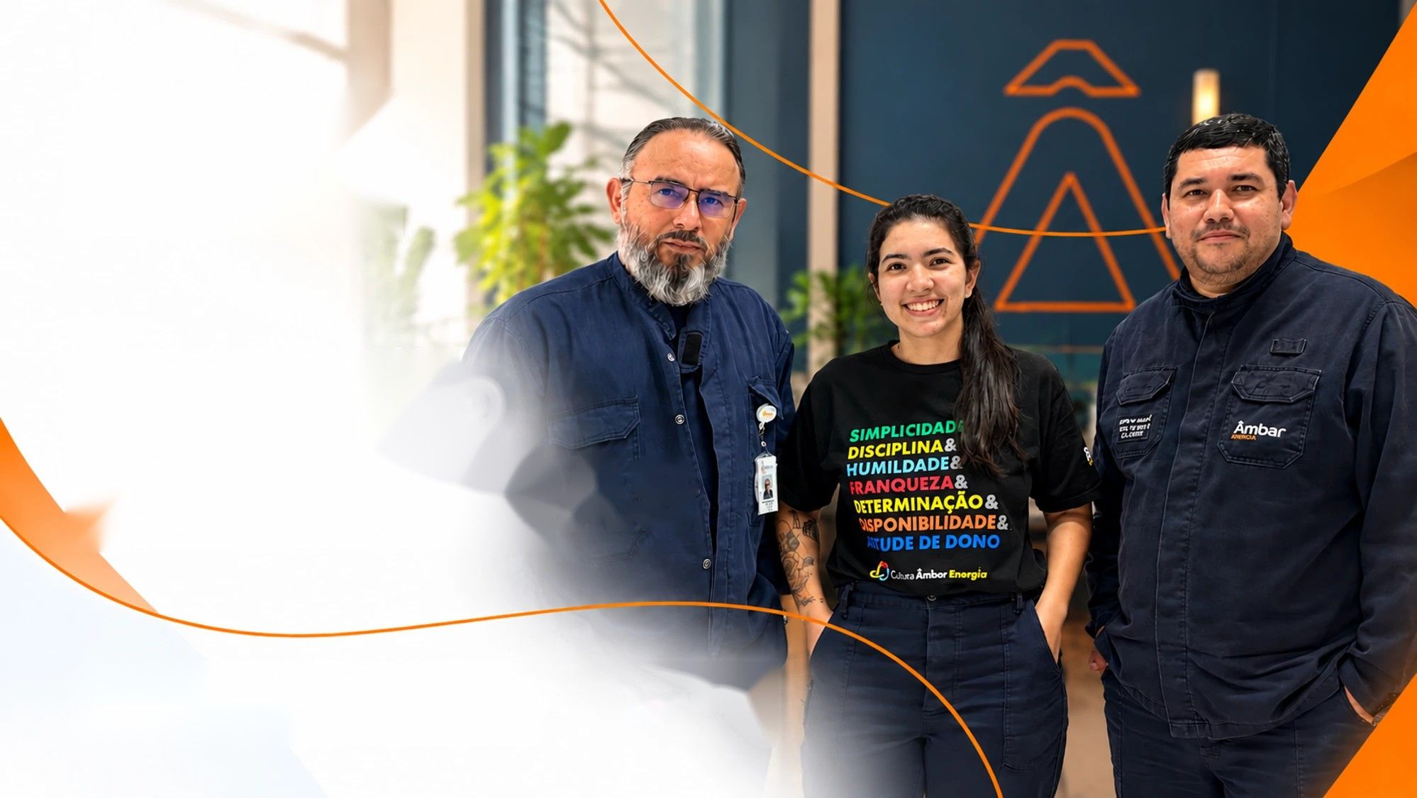 Colaboradores da Âmbar Energia sorrindo em frente ao símbolo da marca
